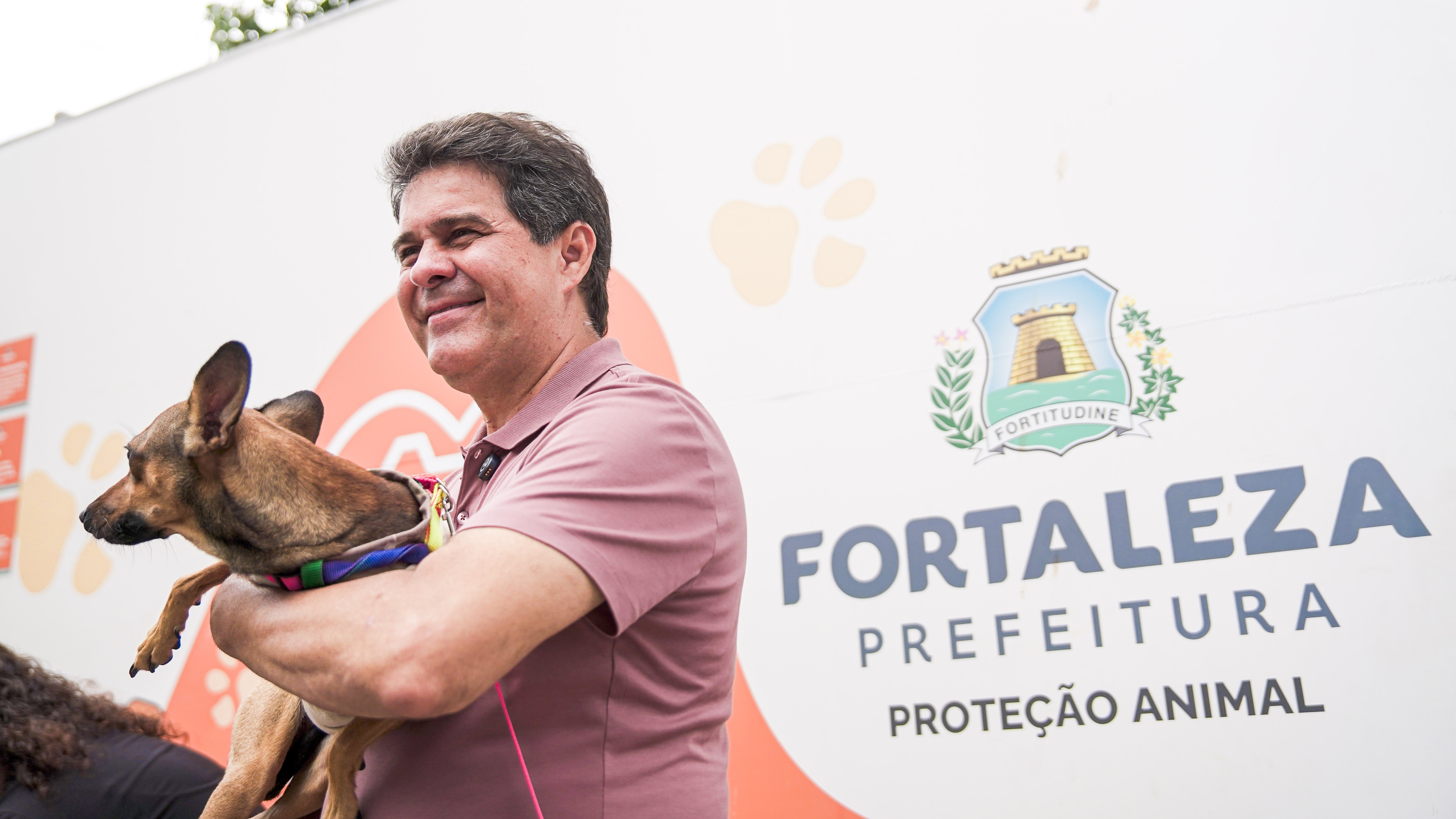 Prefeito Evandro Leitão segura um cachorrinho vira-lata no braço
